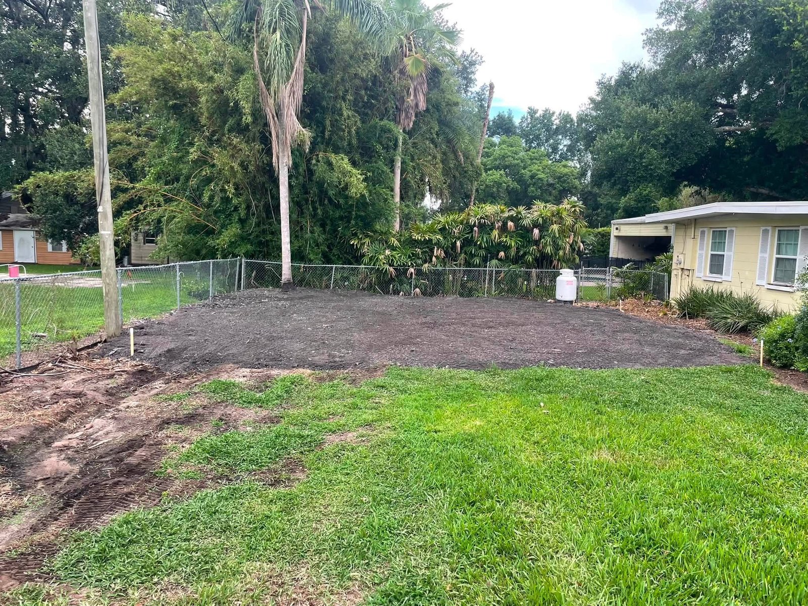 Leveled soil across a residential yard beside a yellow home.